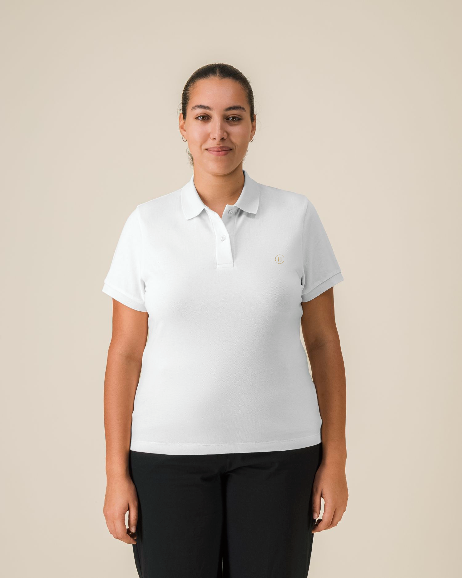 Person wearing a white polo shirt with a logo on a beige background