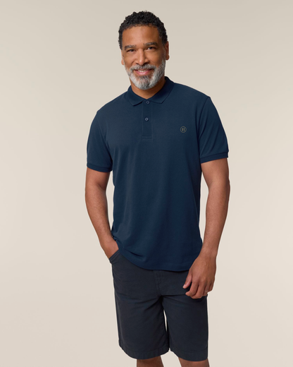 Man wearing a navy polo shirt and shorts on a beige background