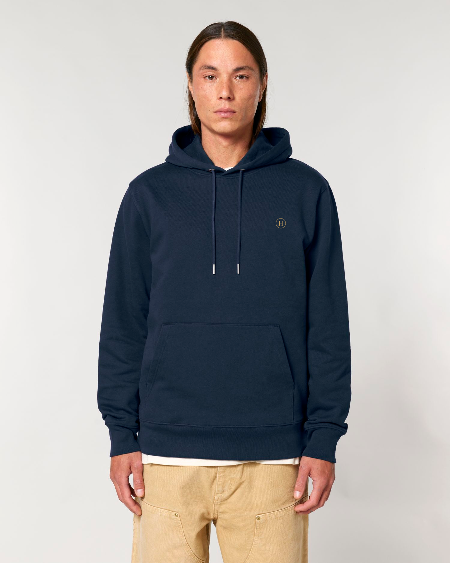 Person wearing a navy blue hoodie with a small logo on a light gray background