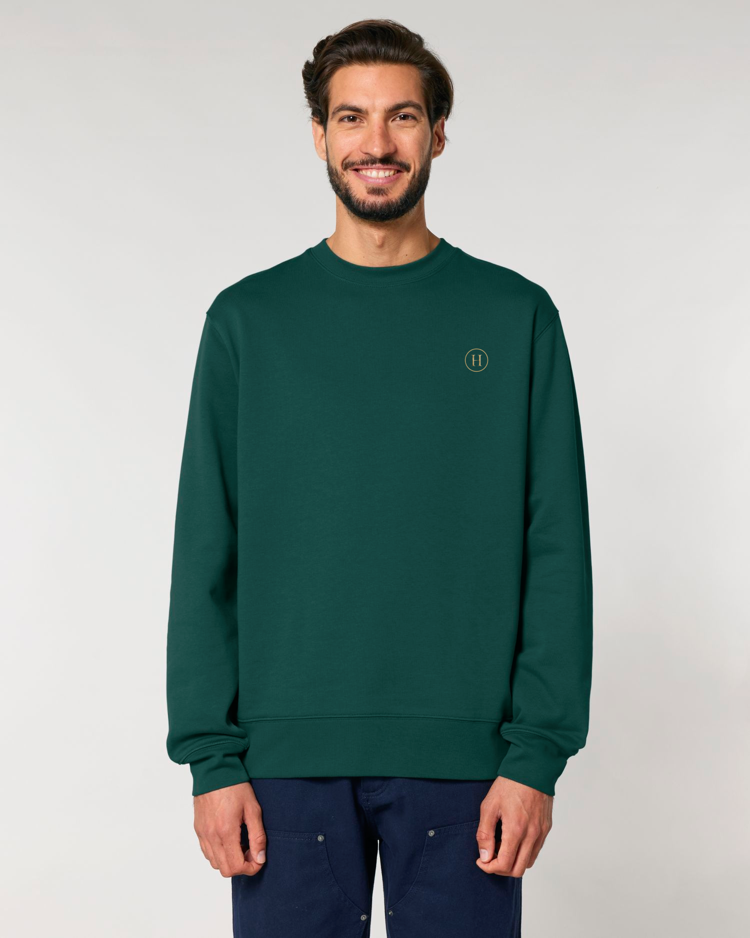 Man wearing a green sweatshirt with a logo on a plain background