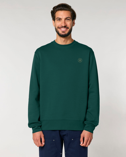 Man wearing a green sweatshirt with a logo on a plain background
