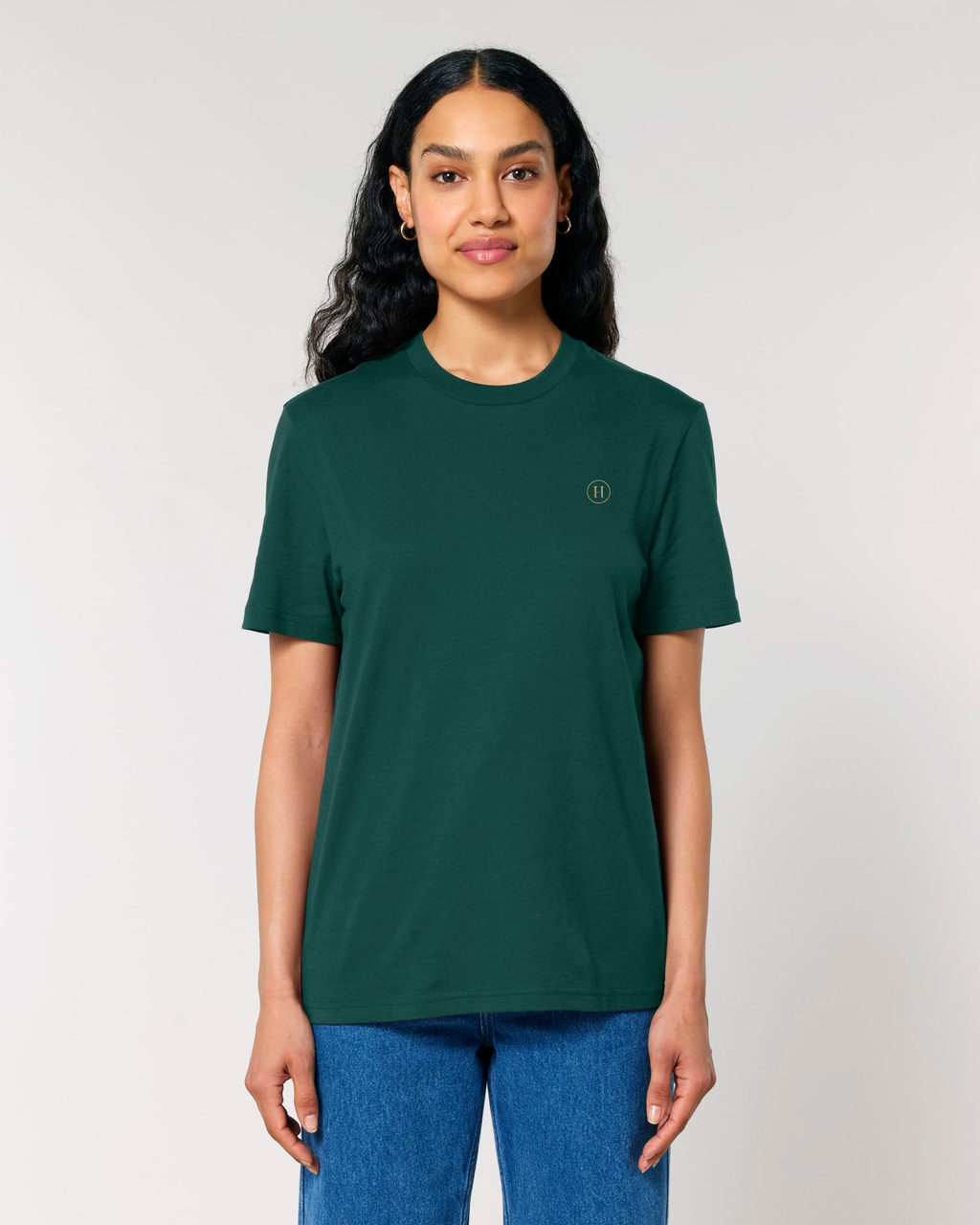 Person wearing a green t-shirt with a small logo on a plain background