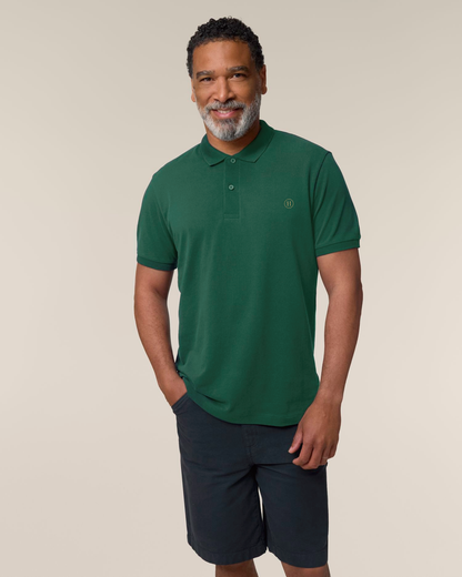 Man wearing a green polo shirt and dark shorts on a beige background