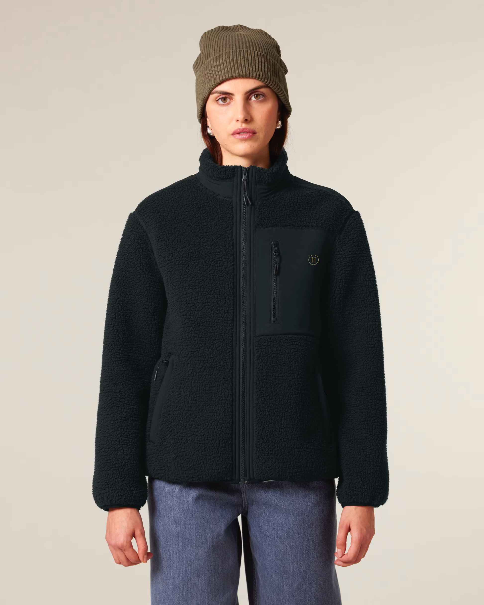 Person wearing a black jacket and green beanie on a plain background