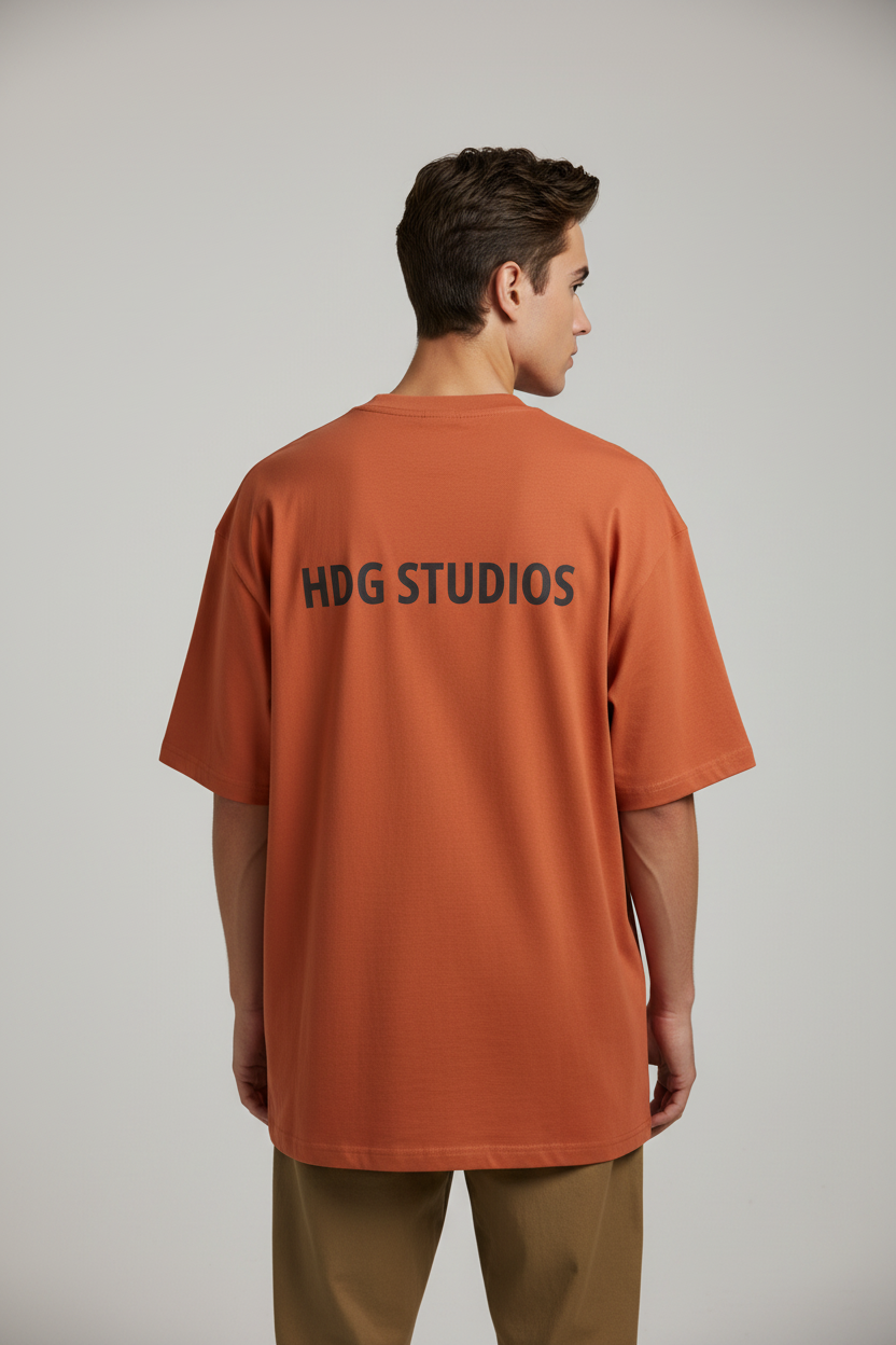 Man wearing an orange t-shirt with 'HOG STUDIOS' text on the back against a plain background